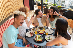 Das Bild zeigt 5 Personen, die an einem Tisch sitzen und gemeinsam essen.