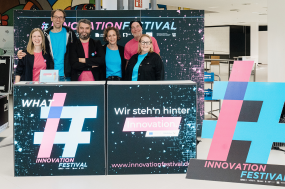 Mehrere Personenstehen an einem Stand mit der Aufschrift Innovation Festival