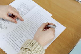 Mensch schreibt mit Stift auf Papier.