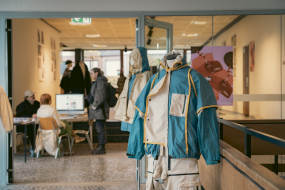 Info-Tisch im Mode-Bereich des Fachbereichs mit Ausstellungsstücken auf Puppen