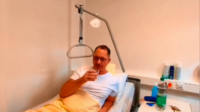 Im Bett liegender Patient trinkt ein Glas Wasser.