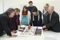 Studierende und Betreuer stehen um einen Tisch und schauen auf einen Plan