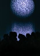 Projektion, die eine Art Steinkugel zeigt, mit Silhouetten von Menschen davor