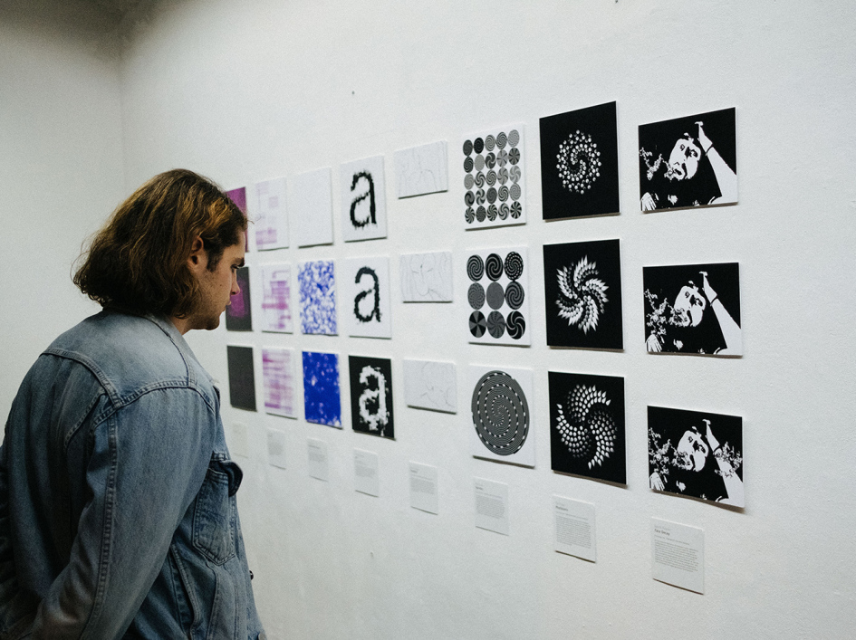 Mann betrachtet eine Reihe generativer Grafiken an der Wand