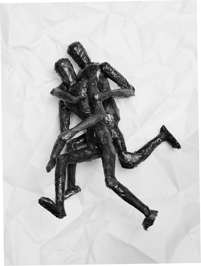 Zwei aus Tape gefertigte Figuren vor einem knittrigen Papierhintergrund