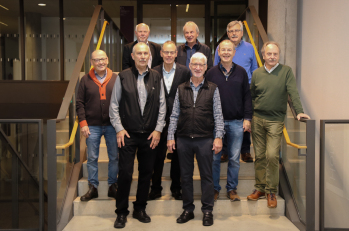 Neun Männer stehen auf einer Treppe und posieren für ein Gruppenfoto.