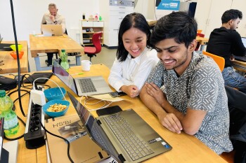 Zwei Studierende sitzen an ihren Laptops.