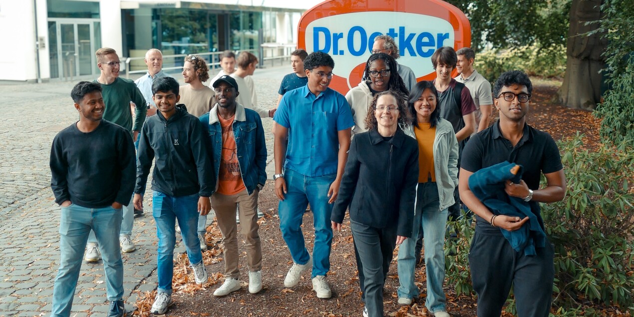 Die Gruppe posiert vor dem Dr. Oetker Emblem