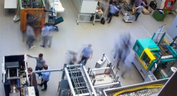 Man hat einen Blick von oben auf Maschinen in der Experimentierhalle, die Kunststoff verarbeiten.