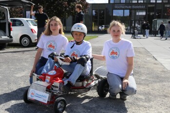 Fahrer Lionel mit Juliane und Laila am Solarauto vor dem HSBI-Gebäude