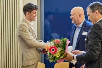 Linus Bröker steht links im Bild und bekommt einen Blumenstrauß überreicht.