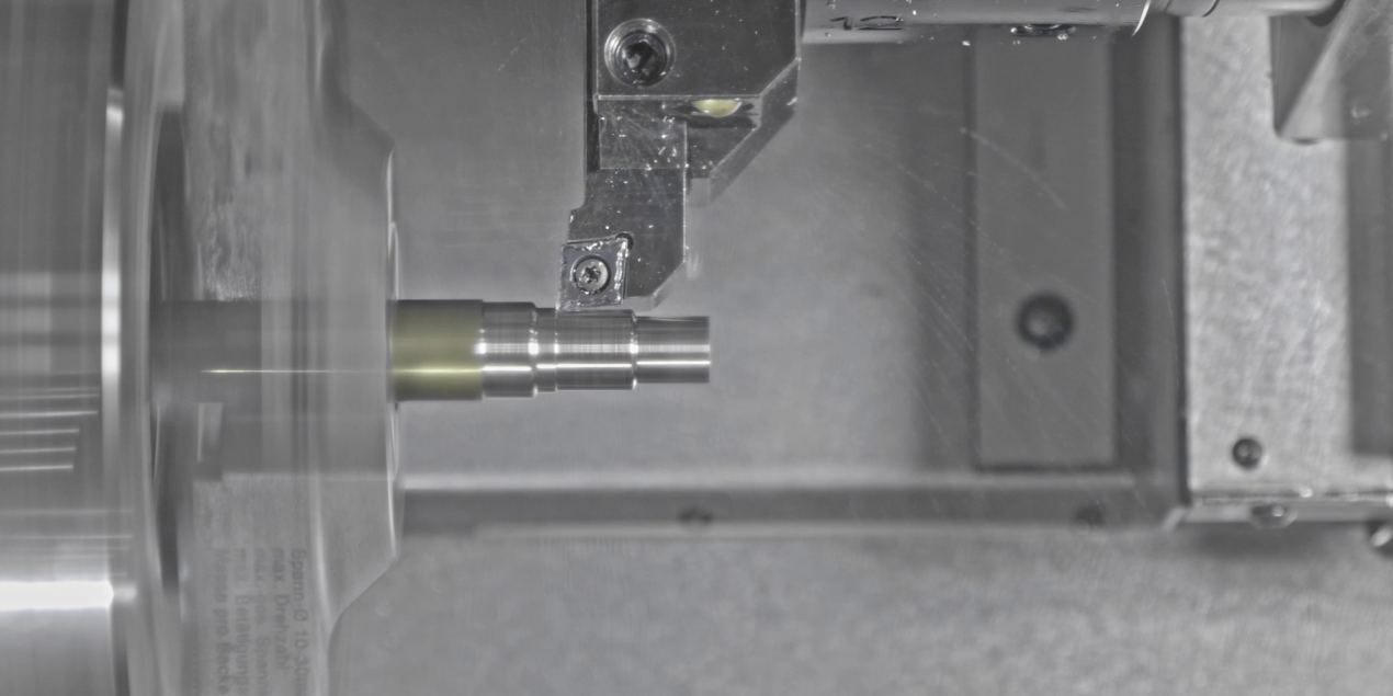 Nahaufnahme eines CNC-Werkzeugs bei der Bearbeitung eines Metallbauteils; die Schneide folgt präzise einem berechneten Werkzeugpfad und trägt Material von der Oberfläche ab.