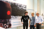 Drei Herren stehen zusammen und sprechen über die nächsten Projektschritte. Links von ihnen sieht man ein Plakat vom Monocab.