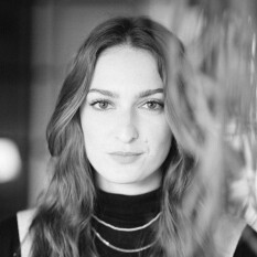 Eine junge Frau schaut in die Kamera. Das Bild ist eine Portraitaufnahme in schwarz-weiß.