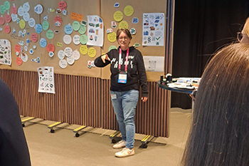 Beatriz García steht vor einer Pinnwand. Daran sind viele Post-Its und Symbole zum Thema Zirkularität angepinnt.