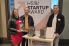 Catharina Schilp steht an einem Tisch vor einer Leinwand auf der HSBI Startup Award geschrieben steht. Mit ihr am Tisch stehen Marius Haacke und Simon Kröger vom Unternehmen Werkzeugbau Berger. Auf dem Tisch steht ein Spritzgießwerkzeug