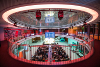 Bild des sogenannten Ovals in der Wissenswerkstadt zu sehen ist der zentrale Raum in der wissenswerkstadt bei einer abendveranstaltung auf der leinwand im bildhintergrund sind die seitenlinien eines fußballfeldes zu erkennen der raum ist rot erleuchtet