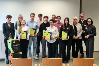 13 Personen stehen für ein Gruppenfoto zusammen