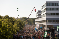 EIne Menschenmente von oben zwischen Bäumen und einem Gebäude