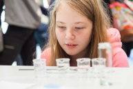 Ein Mädchen schaut sich kleine gefüllte Behälter an