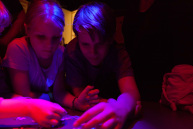 In einem abgedunkelten Raum der nur mit rotem Licht beleuchtet ist, versuchen Kinder ein Puzzle zu legen