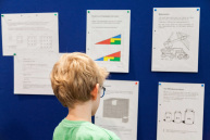 Ein Junge schaut auf ein Wand mit Aufgabenzetteln