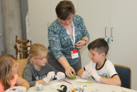 Eine Person erklärt drei Kindern etwas