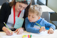 Eine Frau schreibt mit einem Jungen etwas auf einen Zettel