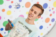 Ein Junge hält einen Stab in der Hand, darüber schwebt ein Gegenstand aus silberner Folie