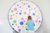 Ein Junge steht vor einer runden gepunkteten Scheibe