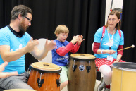 Zwei Erwachsene und ein Kind trommeln