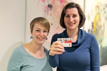 Die beiden Frauen stehen nebeneinander, die rechte hält ihren Spenderausweis in die Kamera.