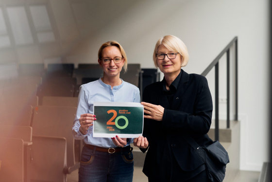 Foto: Bauer und Schramm-Wölk halten ein Din A 4 Papier mit 20 Jahren Studienfonds OWL in die Kamera