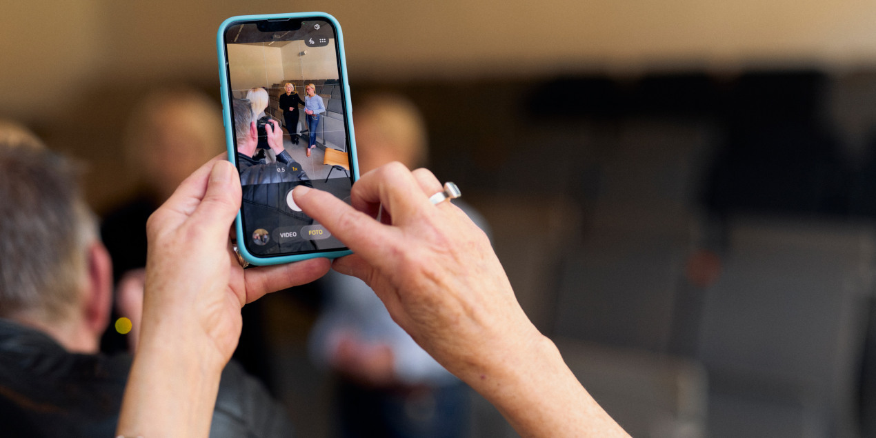 Foto: Eine Person fotografiert Bauer und Schramm-Wölk mit einem handy