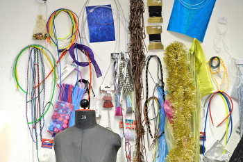 Hinter einer Schneiderpuppe hängen an der Wand verschiedene Bänder und Stoffe