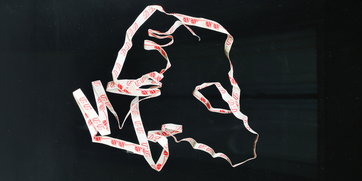 Ein Wäschezeichenband mit den Initialien DD vor einem schwarzen Hintergrund