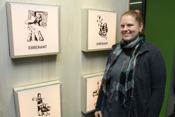 Studentin steht vor ihren vier Illustrationen mit Märchenfiguren zum Thema Ehrenamt.