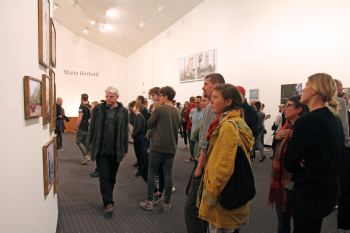 Personen stehen vor den Bildern und schauen sie sich an.