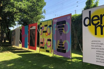 auf einer Grünfläche stehen sieben große Plakatewände