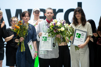 Drei Personen mit Blumensträuen und Urkunden