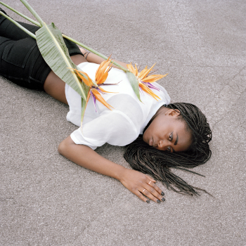 Eine Frau liegt auf dem Boden, eine Blume liegt auf ihrem Rücken