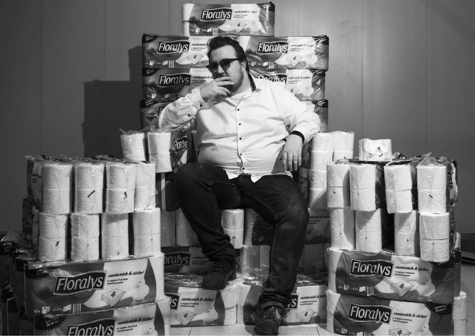 Eine Fotografie von einem Mann, der auf einem Thron aus Klopapier sitzt