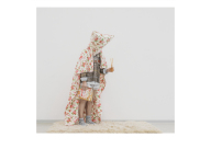 Ein Foto von einem Mensch mit Bettdecke um den Körper und Duftstäbchen und Zeitschrift in den Händen