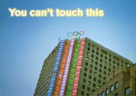 Ein Hochhaus auf dem die olypischen Ringe angebracht sind mit dem Schriftzung You cant't touch this