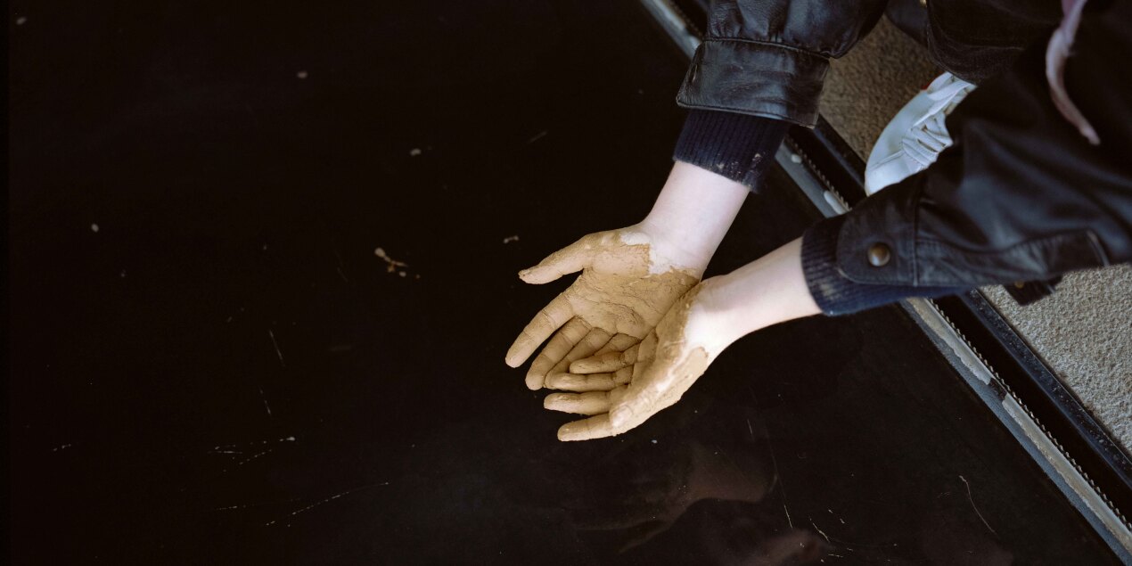 Schlammverschmierte Hände, die von oben fotografiert wurden