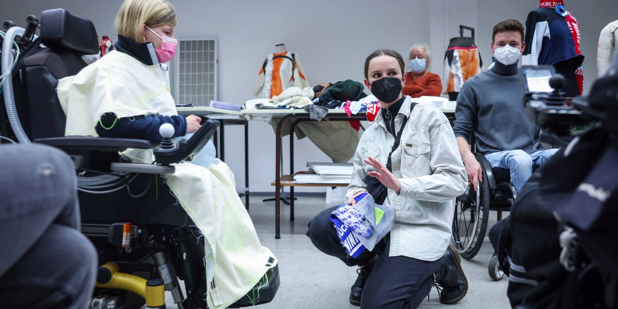 Eine Rollstuhlfahrerin probiert Kleidungsstücke an