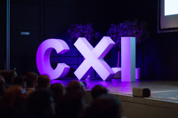 Die Buchstaben CXI sind in lila angeleichtet groß auf einer Bühne zu sehen.