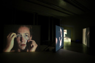 In einem dunklen Raum sind auf großen Leinwänden Fotos von Frauen projiziert