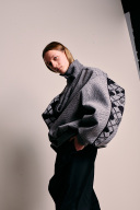 Eine Person steht vor einer weißen Wand und schaut in die Kamera.