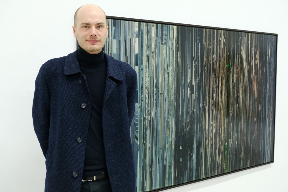 Männliche Person steht neben seinem Bild.